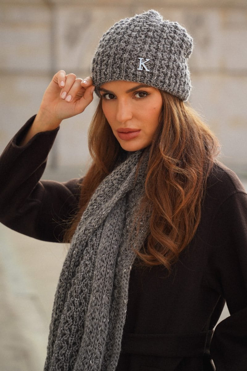 Detal metalowej ozdoby w kształcie litery „K” na przodzie czapki, dodający elegancji kompletowi | KAMEA | Spironik.pl