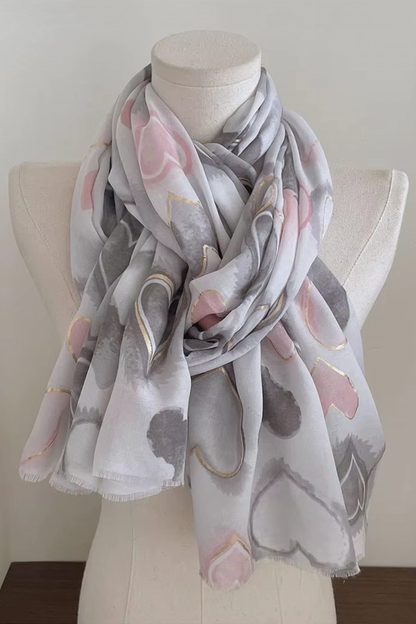 Szal w szarościach i różu na tle jasnej powierzchni, prezentujący elegancki design | KAMEA | Spironik.pl