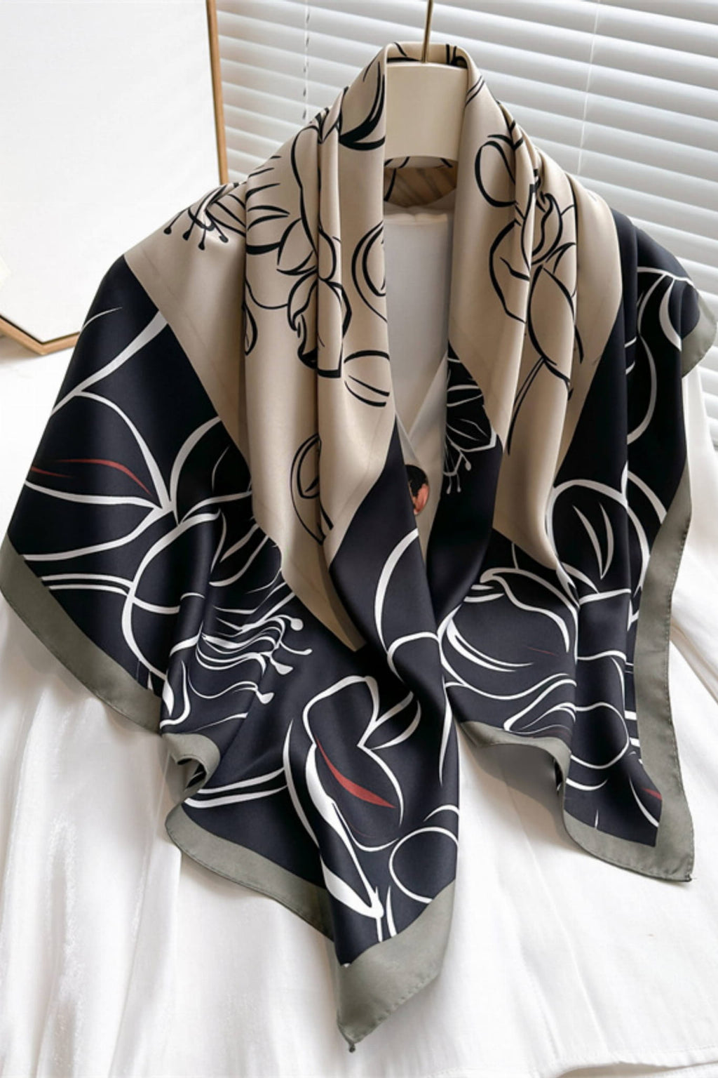 Detal apaszki z delikatnym kwiatowym szkicem na tle czerni i beżu | KAMEA | Spironik.pl