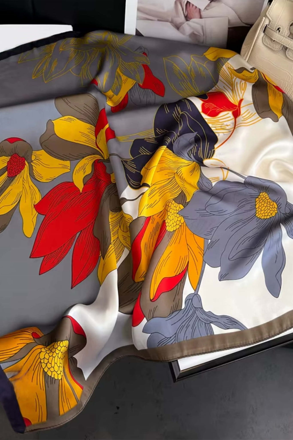 Detal apaszki satynowej z wyrazistym wzorem kwiatów w kolorach czerwonym i żółtym na szarym tle | KAMEA | Spironik.pl