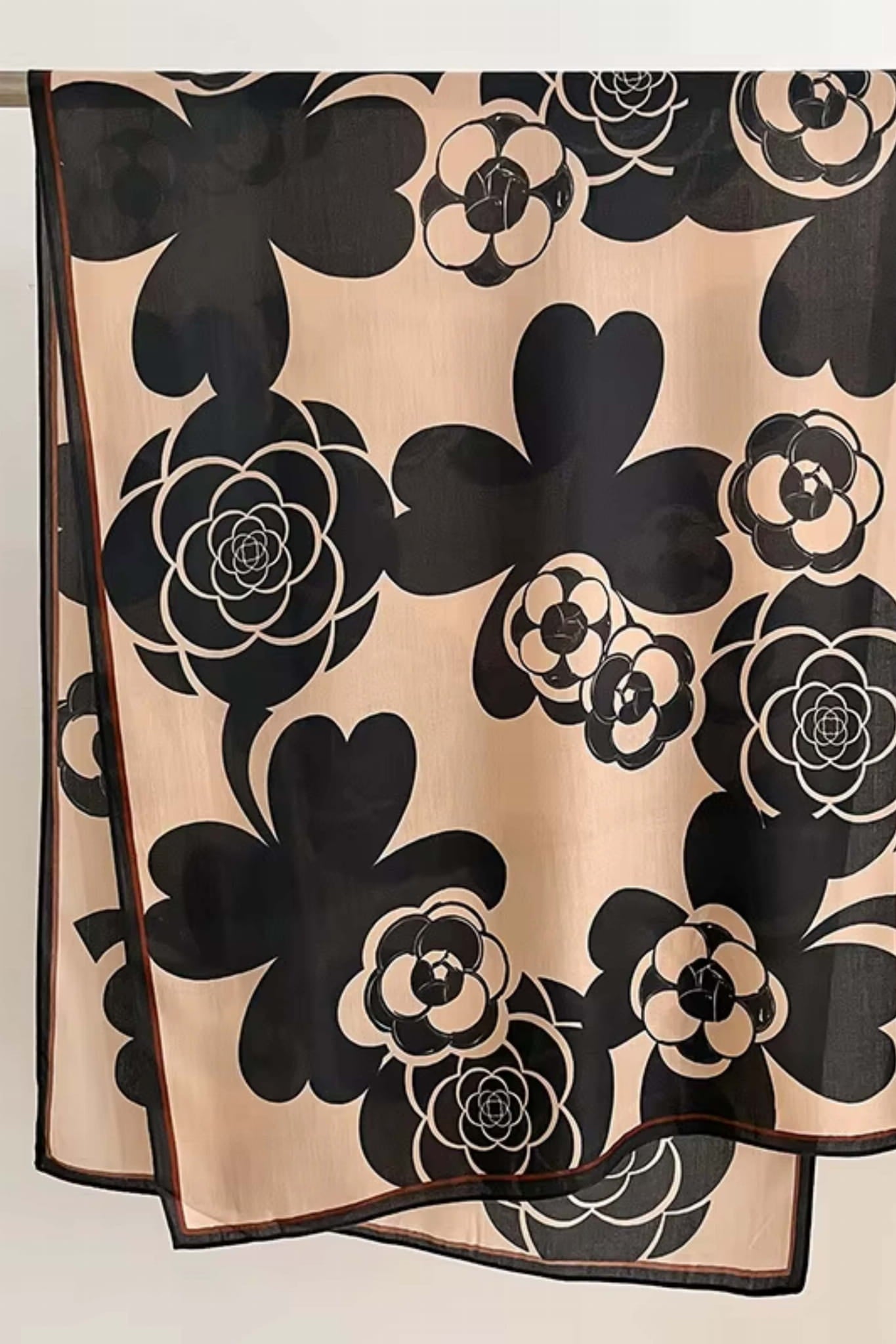 Detal beżowo-czarnego szala z czerwonym akcentem, ukazujący graficzne kwiaty | KAMEA | Spironik.pl