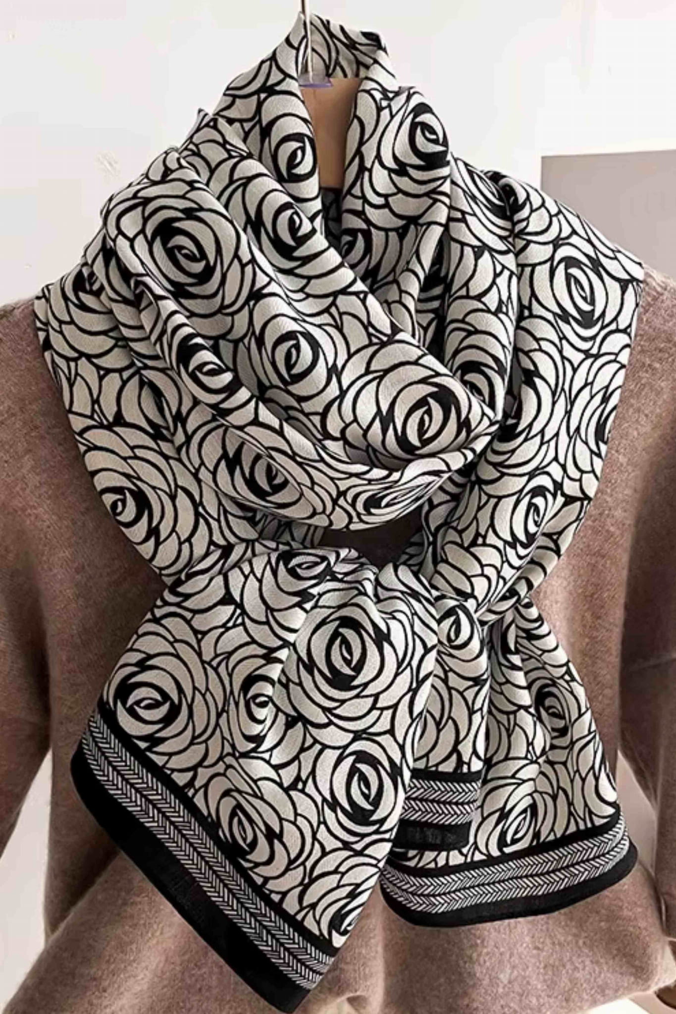 Elegancki szal w czarne róże, prezentowany na tle klasycznego płaszcza, doskonały dodatek do stylizacji | KAMEA | Spironik.pl