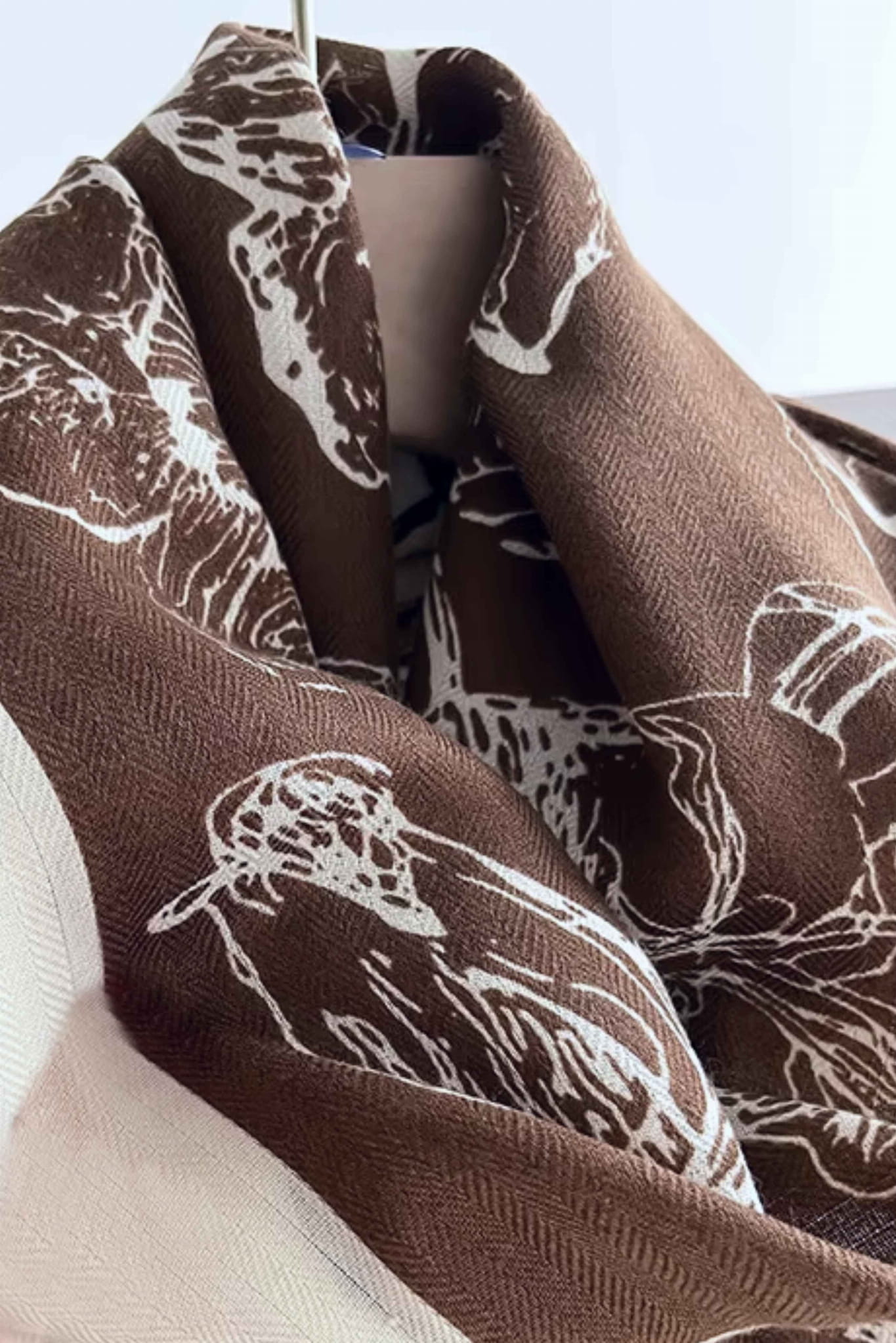 Szal brązowo-ecru w użyciu jako elegancka narzutka na ramionach, doskonały dodatek do garderoby | KAMEA | Spironik.pl