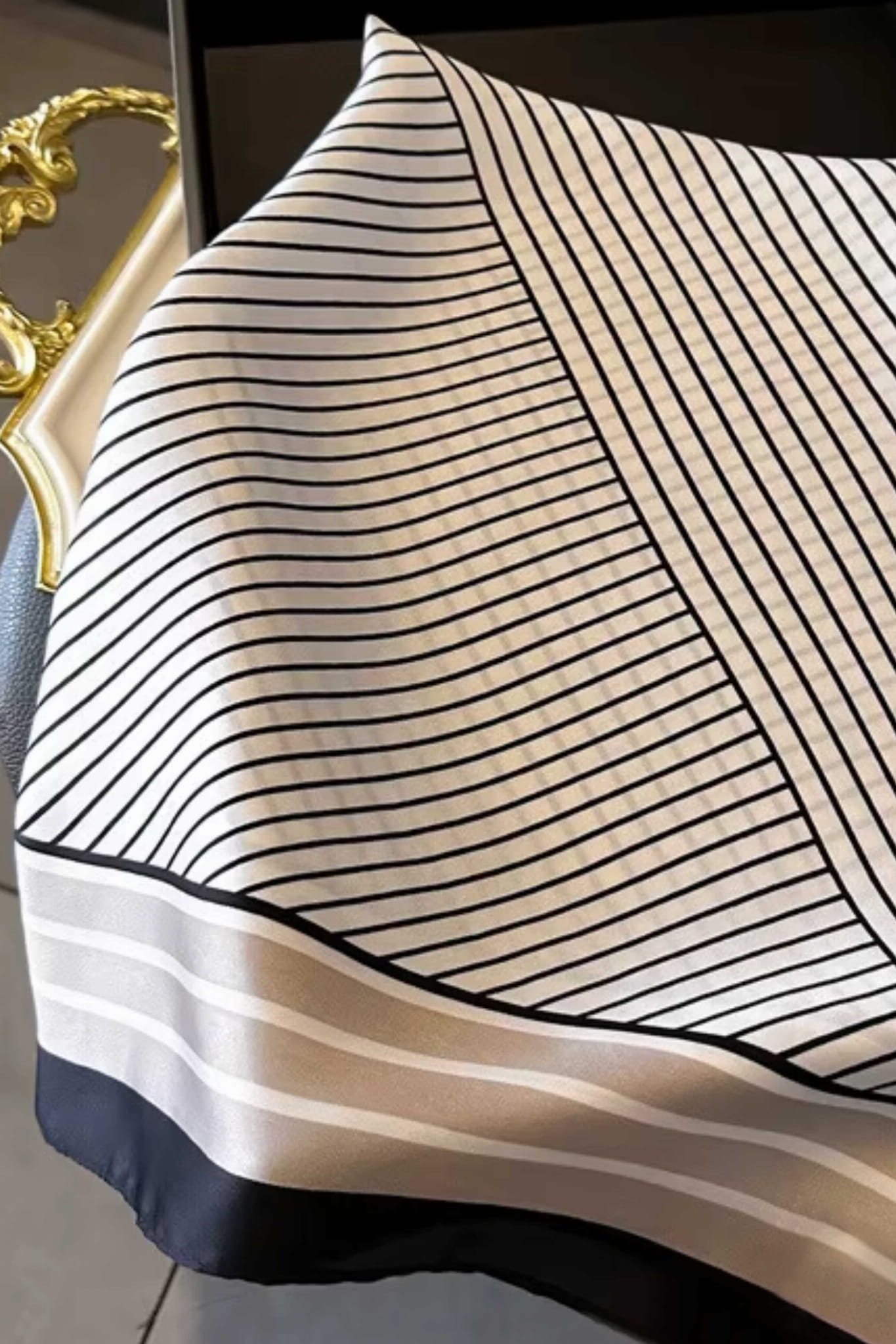 Detal apaszki z geometrycznym wzorem w poziome i ukośne paski w kolorach beżowym, białym i czarnym | KAMEA | Spironik.pl