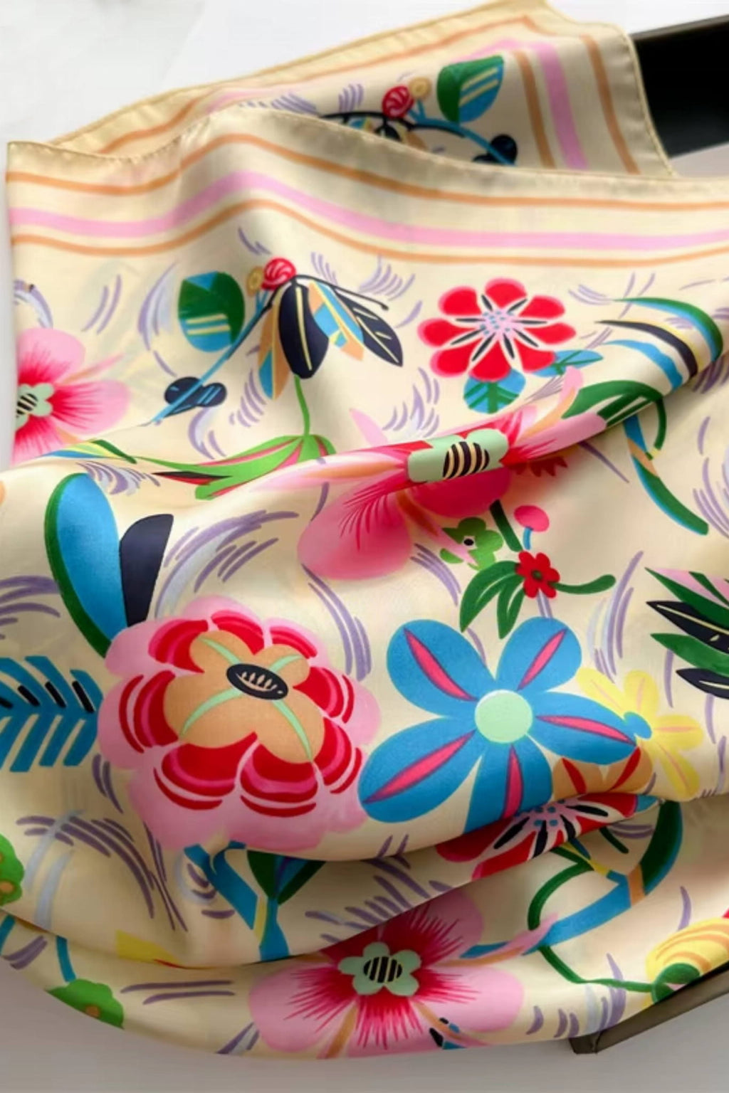 Widok apaszki satynowej z boku, prezentujący jej wymiary 70x70 cm i pastelowe tło | KAMEA | Spironik.pl