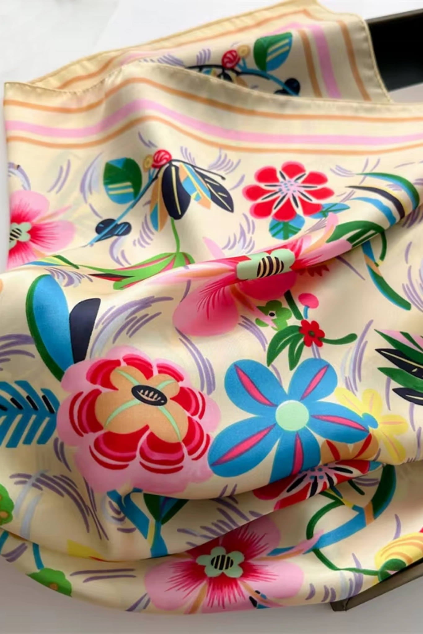 Widok apaszki satynowej z boku, prezentujący jej wymiary 70x70 cm i pastelowe tło | KAMEA | Spironik.pl