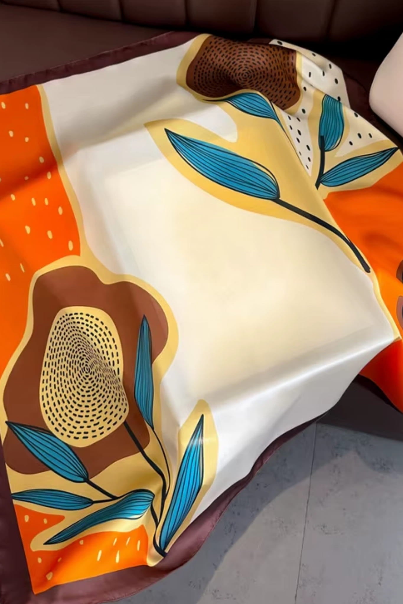 Detal apaszki z graficznymi liśćmi i kwiatami w odcieniach kremu, bursztynu i pomarańczy | KAMEA | Spironik.pl