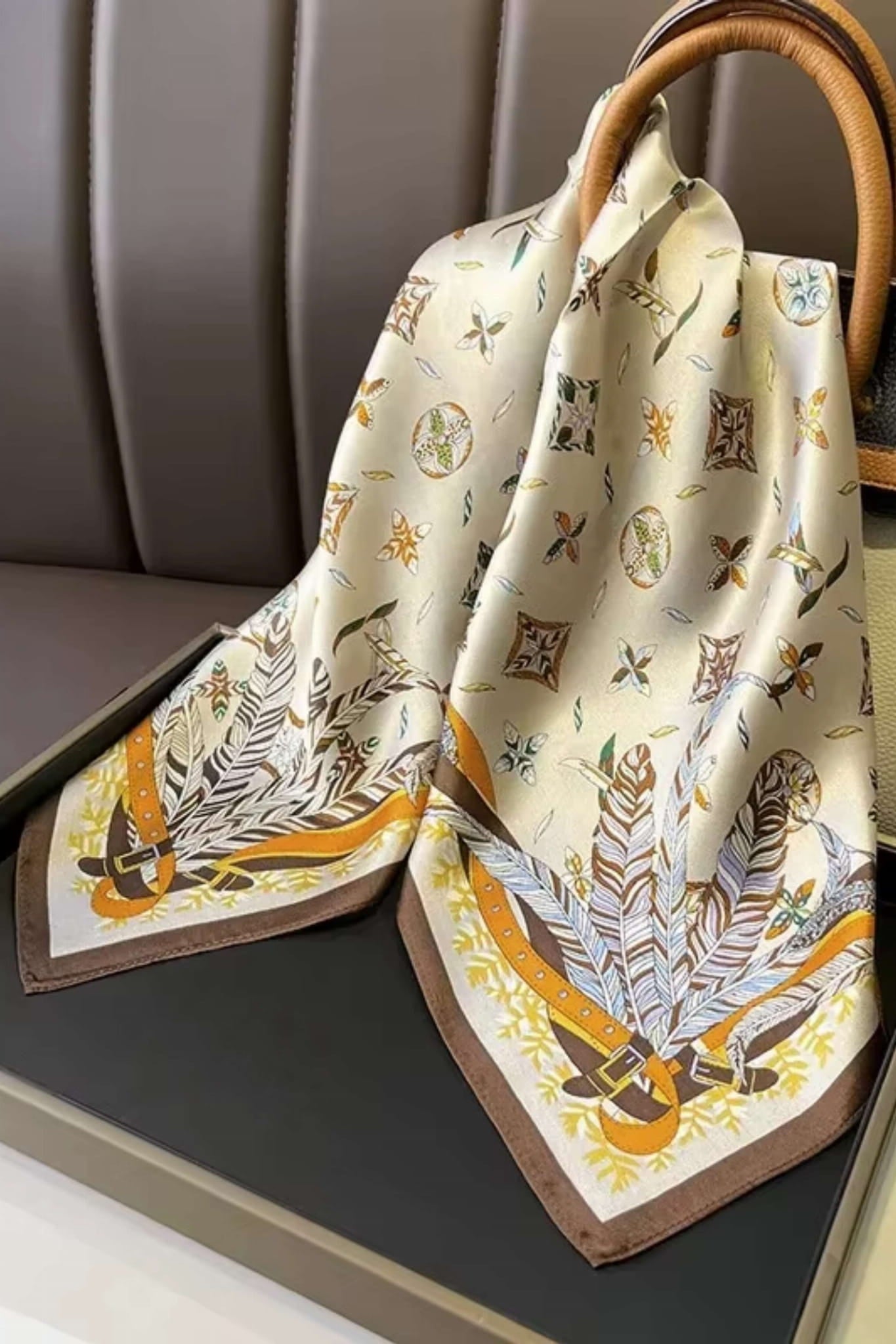 Detal satynowej apaszki z brązowo-żółtymi akcentami, ukazujący ornamenty i geometryczne kształty | KAMEA | Spironik.pl