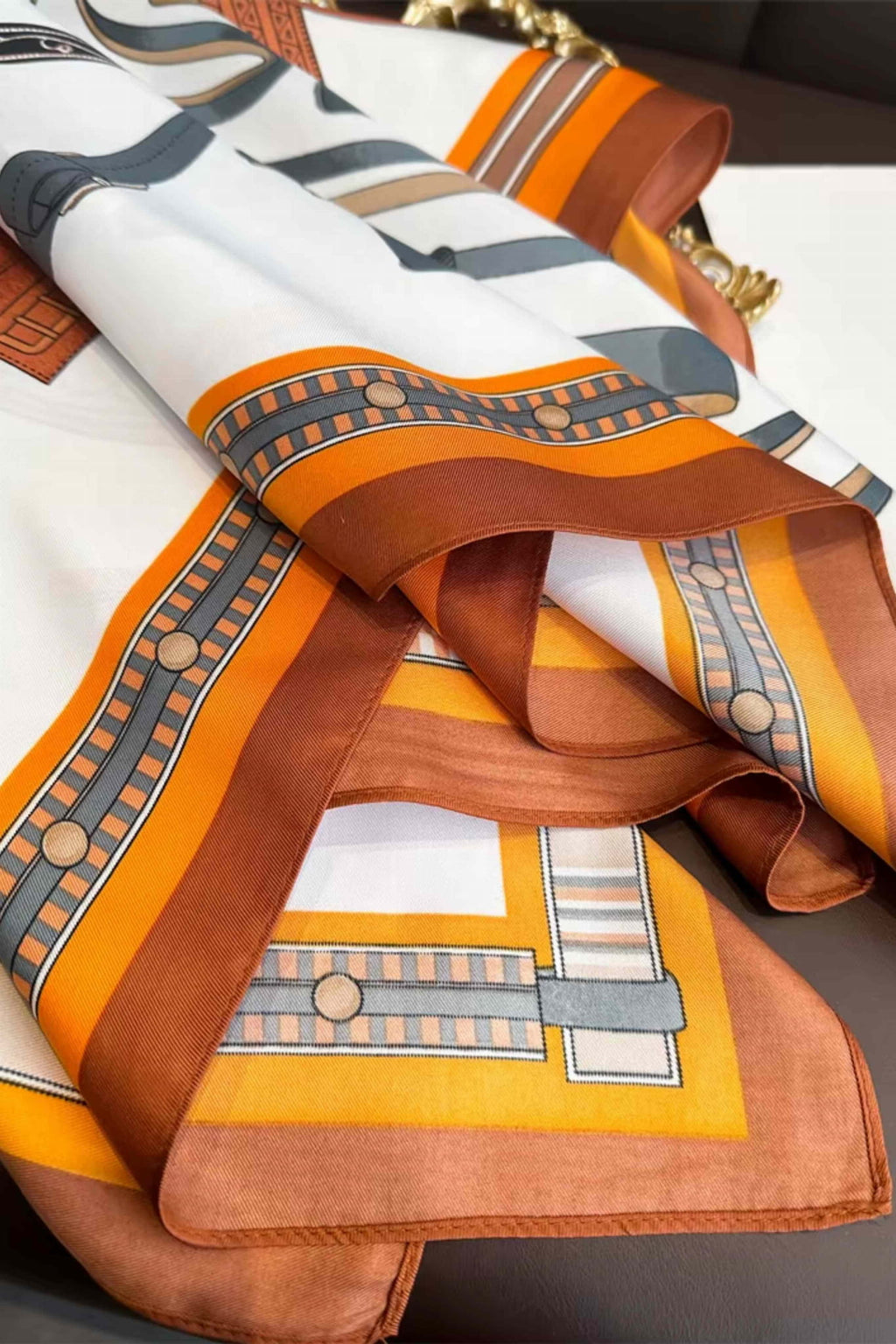 Apaszka w użyciu jako stylowy dodatek do płaszcza, w kolorach brązu i bieli | KAMEA | Spironik.pl