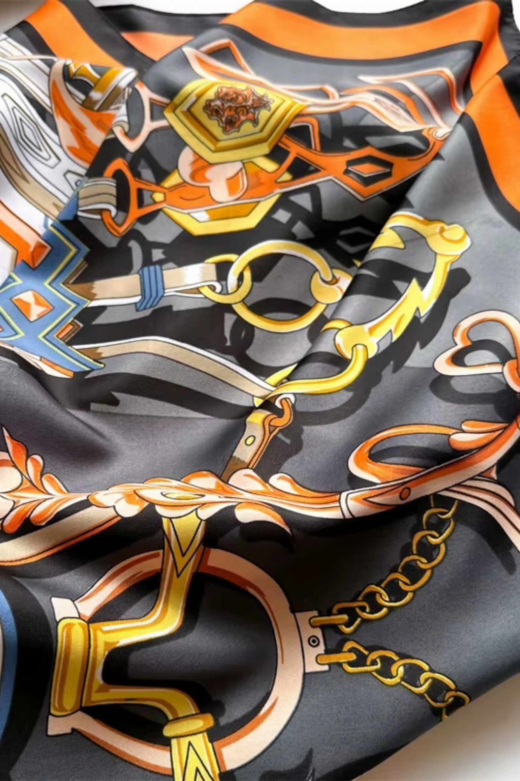 Zbliżenie na motyw łańcuchów i ozdobnych klamer w apaszce czarno-pomarańczowej | KAMEA | Spironik.pl