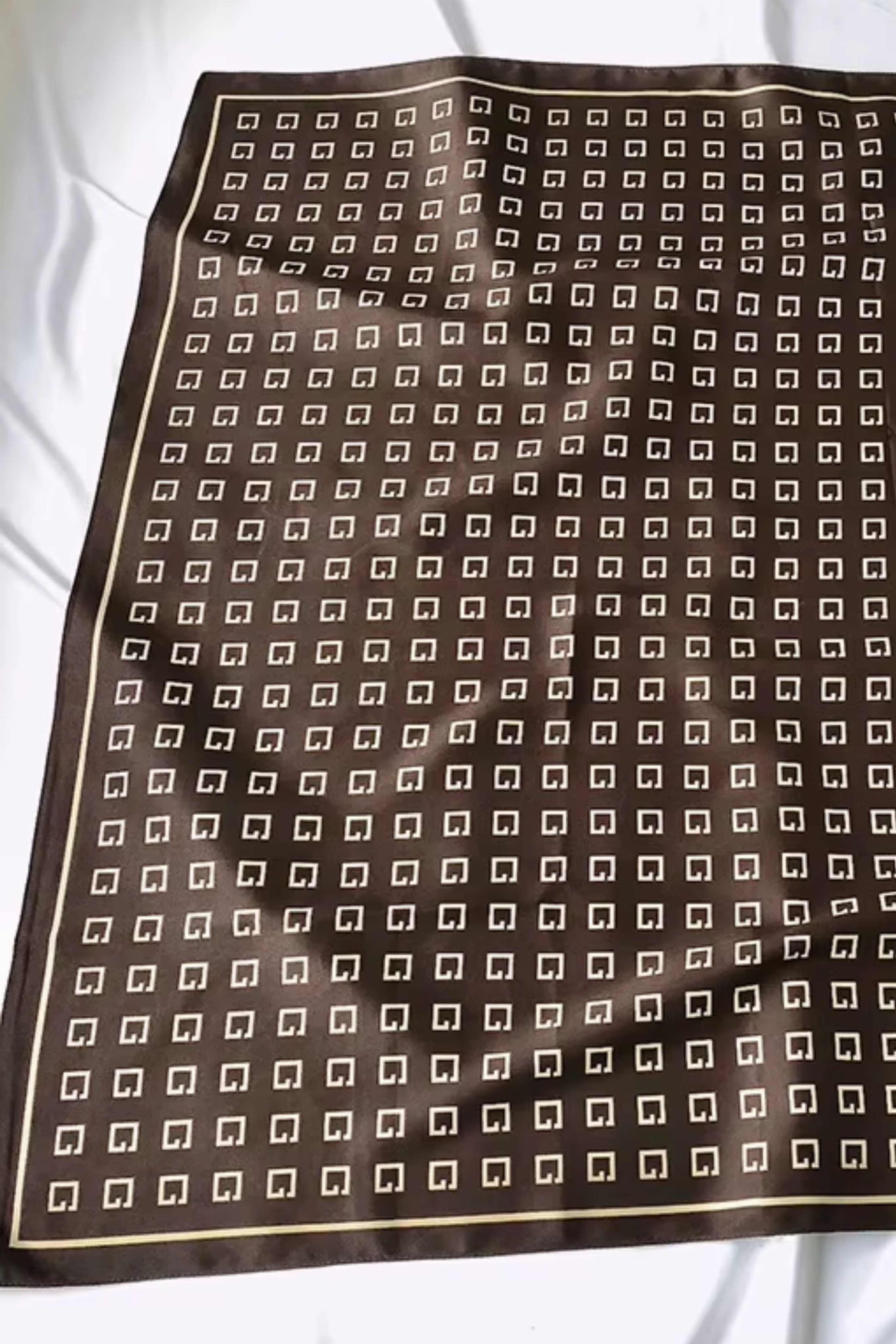 Detal geometrycznego wzoru z literą „G” na brązowej apaszce | KAMEA | Spironik.pl