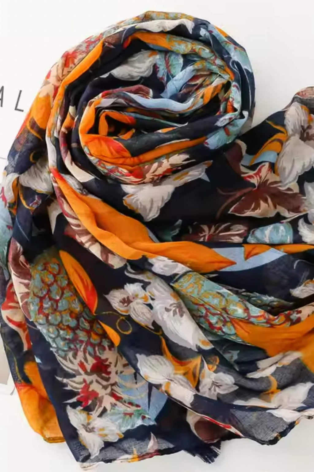 Detal wzoru na szalu: pomarańczowe liście, ananasy i kremowe kwiaty na granatowym tle | KAMEA | Spironik.pl