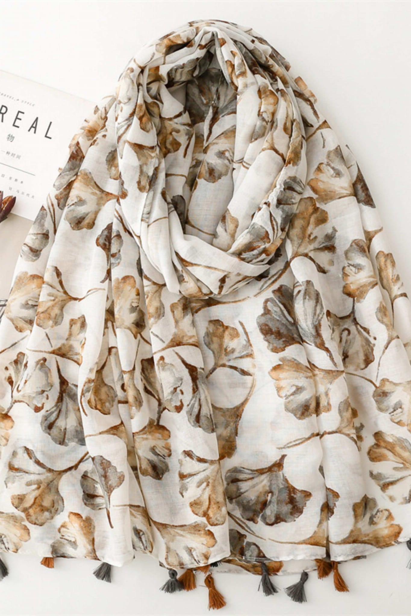 Detal beżowego szala z nadrukiem liści, ukazujący subtelną fakturę materiału | KAMEA | Spironik.pl