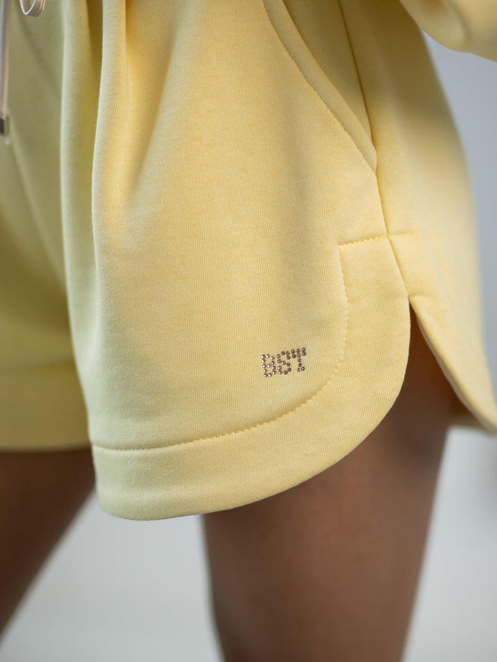 Wygodne spodenki dresowe z zakładkami, kieszeniami i subtelnym logowaniem na nogawce w intensywnym żółtym kolorze | Bastet | Spironik.pl