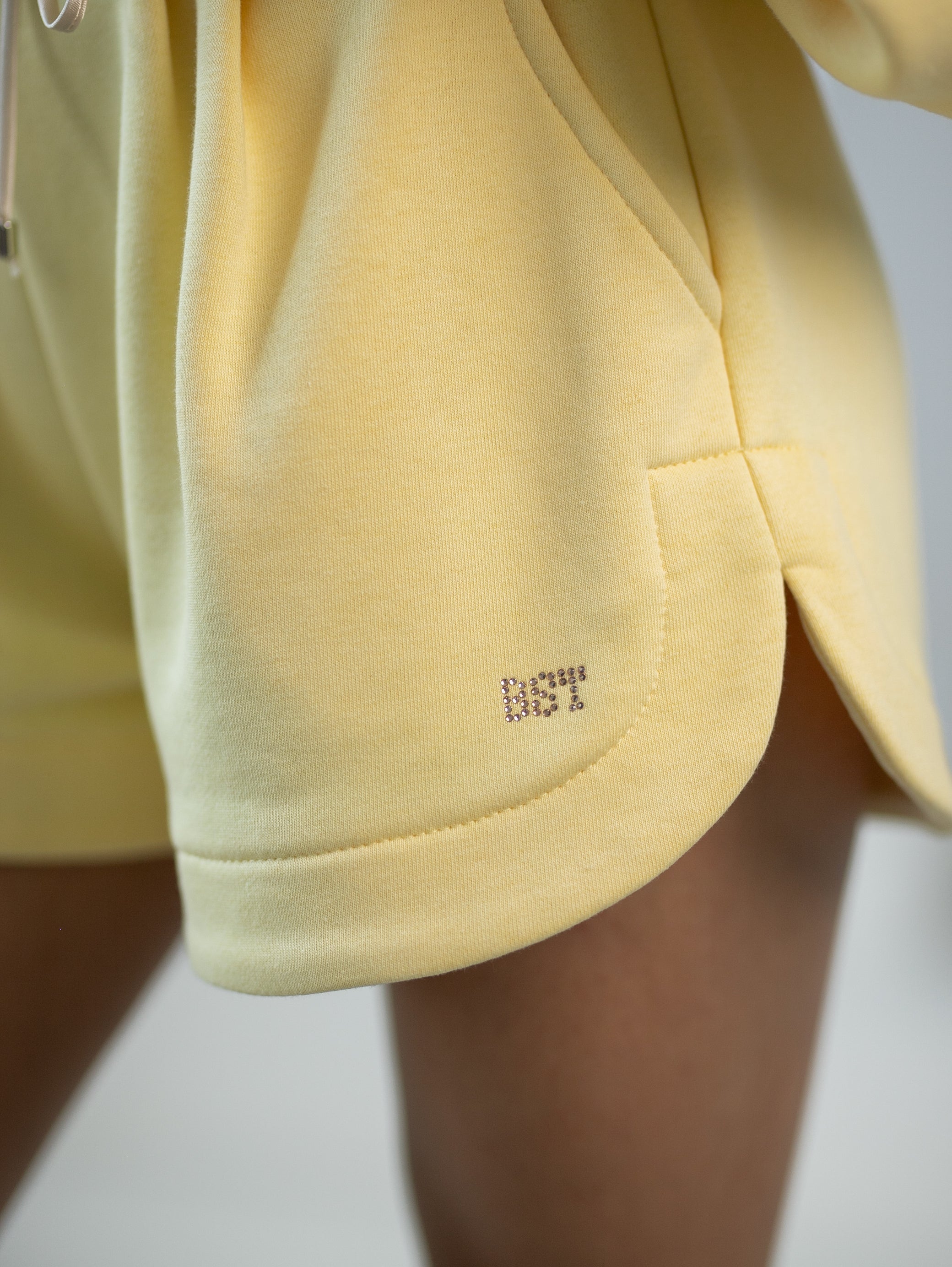 Wygodne spodenki dresowe z zakładkami, kieszeniami i subtelnym logowaniem na nogawce w intensywnym żółtym kolorze | Bastet | Spironik.pl